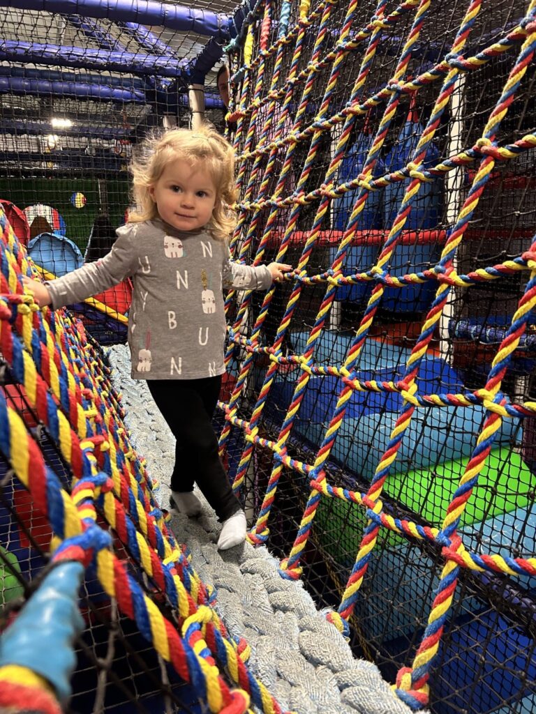 Child enjoying the soft play cargo net